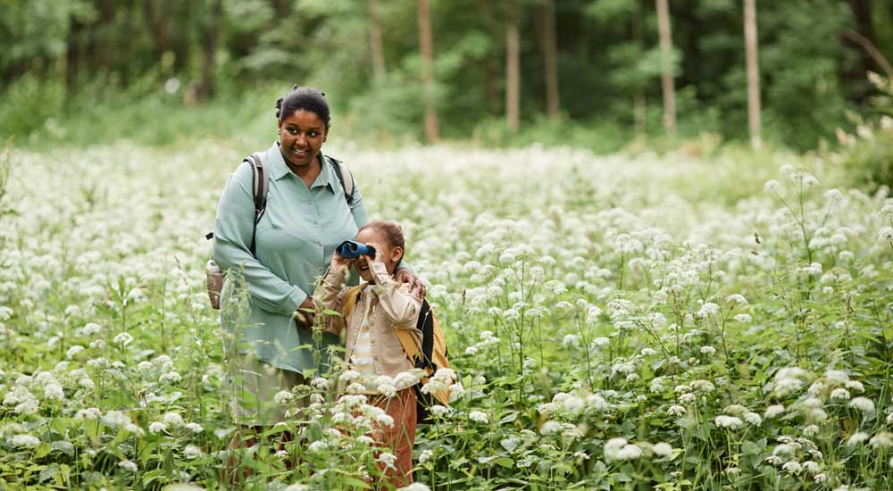 woman and girl in field of flowers with binoculars