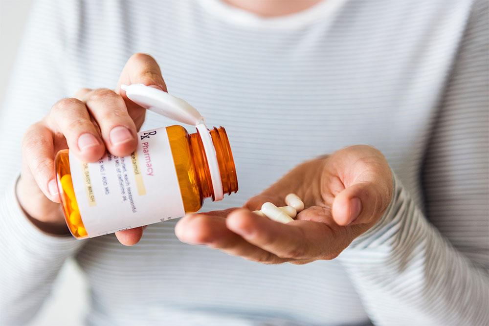 person hands with pill bottle and pills