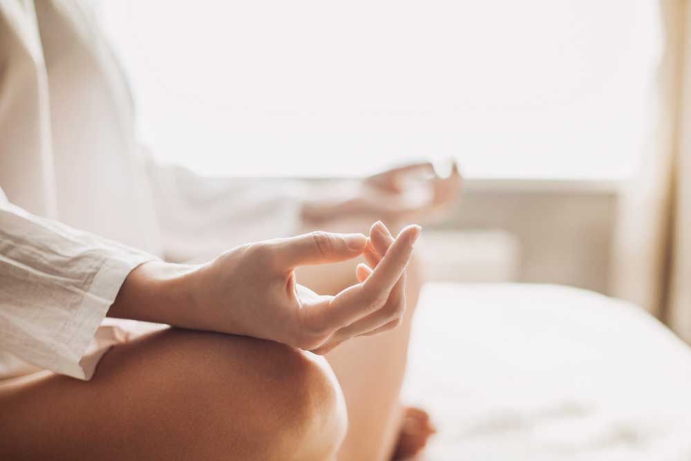 close up of hands on crossed legs while person meditates