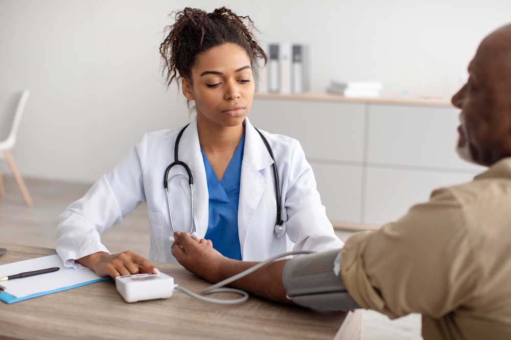woman in white coat taking blood pressure of man