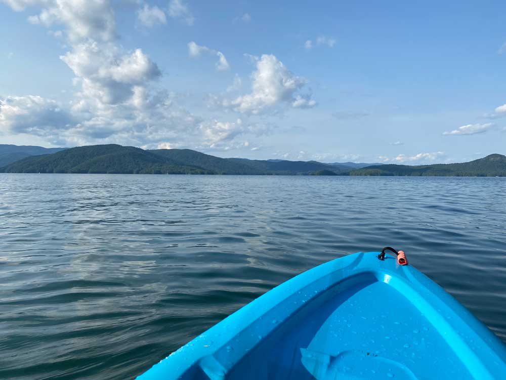 tip of kayak on lake with mountains in distance