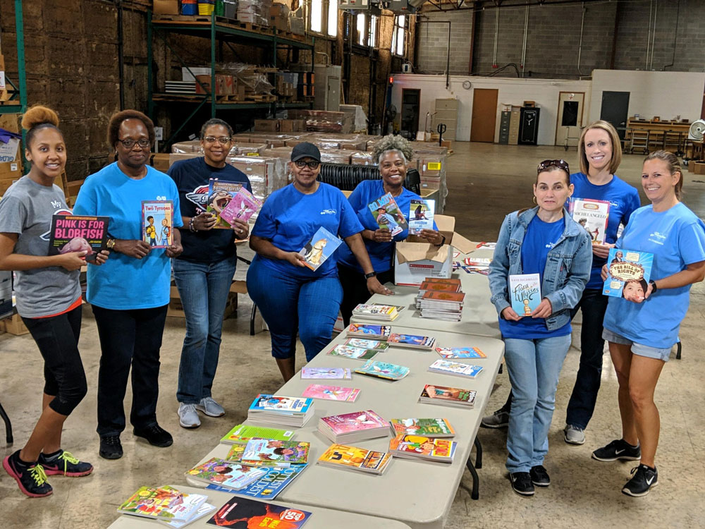 group of employees hold books at donation drive