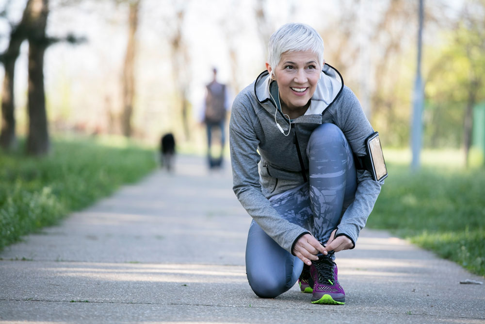 older woman tying shoes in park